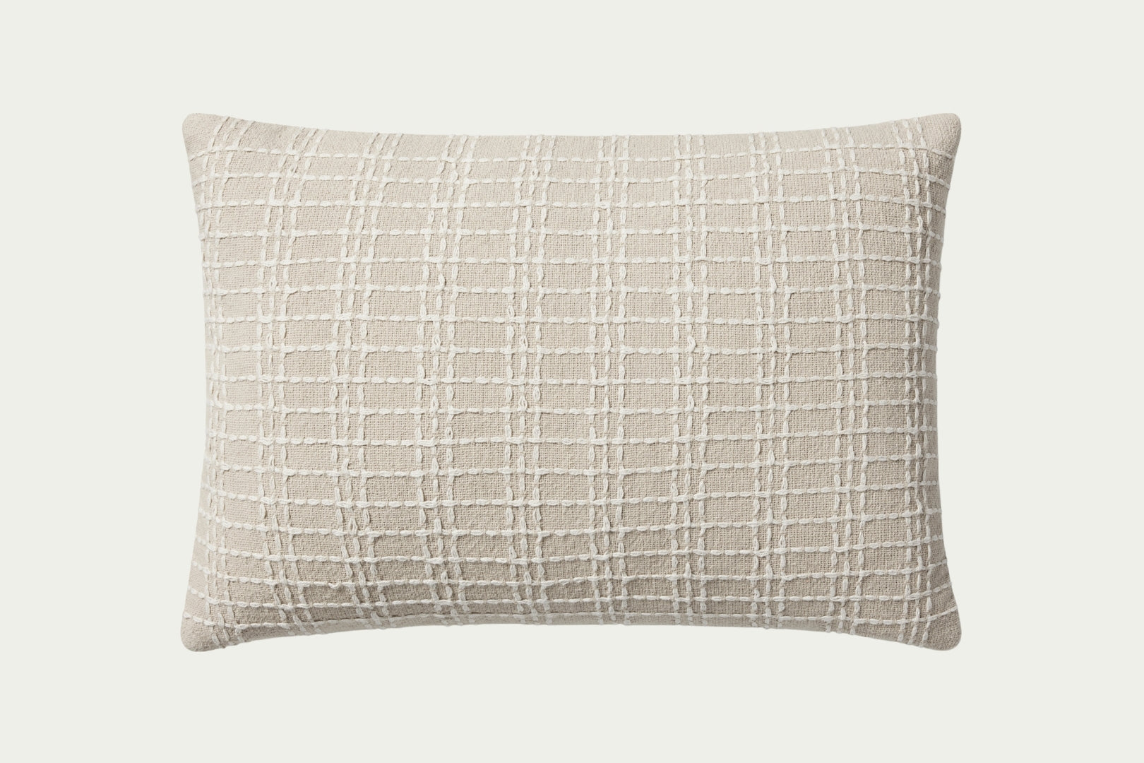 This beige and ivory lumbar throw pillow features a stitched grid design for texture. Made of cotton, it measures 16 by 26 inches, perfect for styling in living rooms and bedrooms.