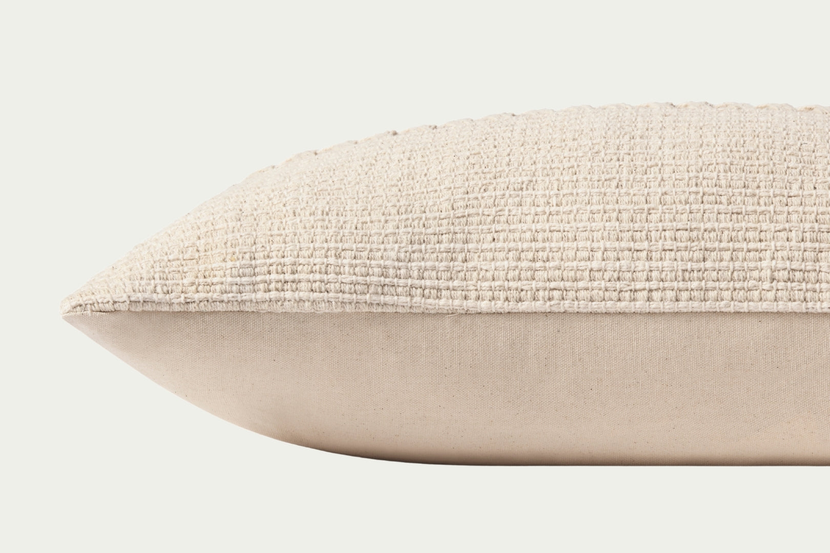 Neutral ivory lumbar throw pillow with a textured, woven stripe across its center, made of cotton, and other materials are 27 inches long by 12 inches tall.