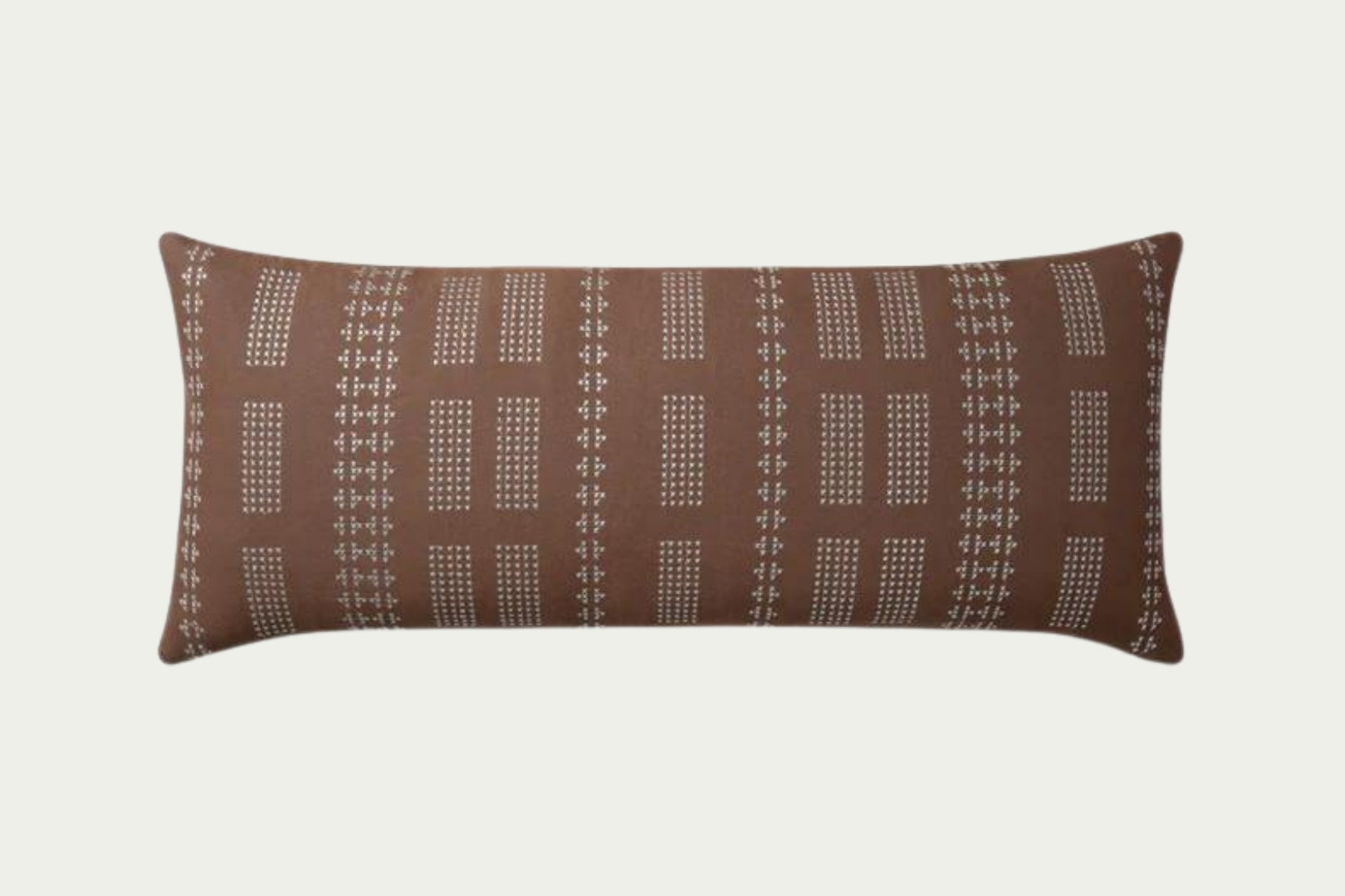 Geometric embroidery that draws the eye toward it. In Clay and Mist, a warm neutral brown with off-white details in a 35-inch by 13-inch rectangular throw pillow.
