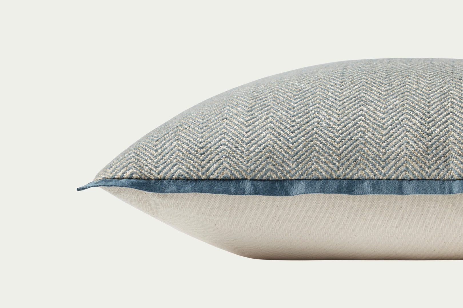 This soft blue hand-stitched herringbone modern throw pillow features a darker blue piping for a polished look.