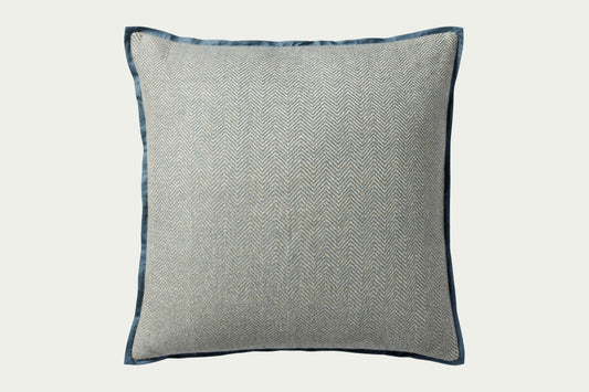 This soft blue hand-stitched herringbone modern throw pillow features a darker blue piping for a polished look.